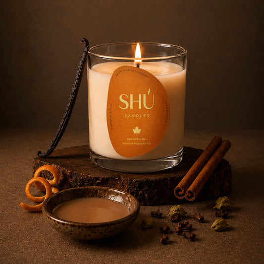 SHÚ Cinnamon Chai soy candle with vanilla pod, cinnamon sticks, cardamom and a bowl of chai